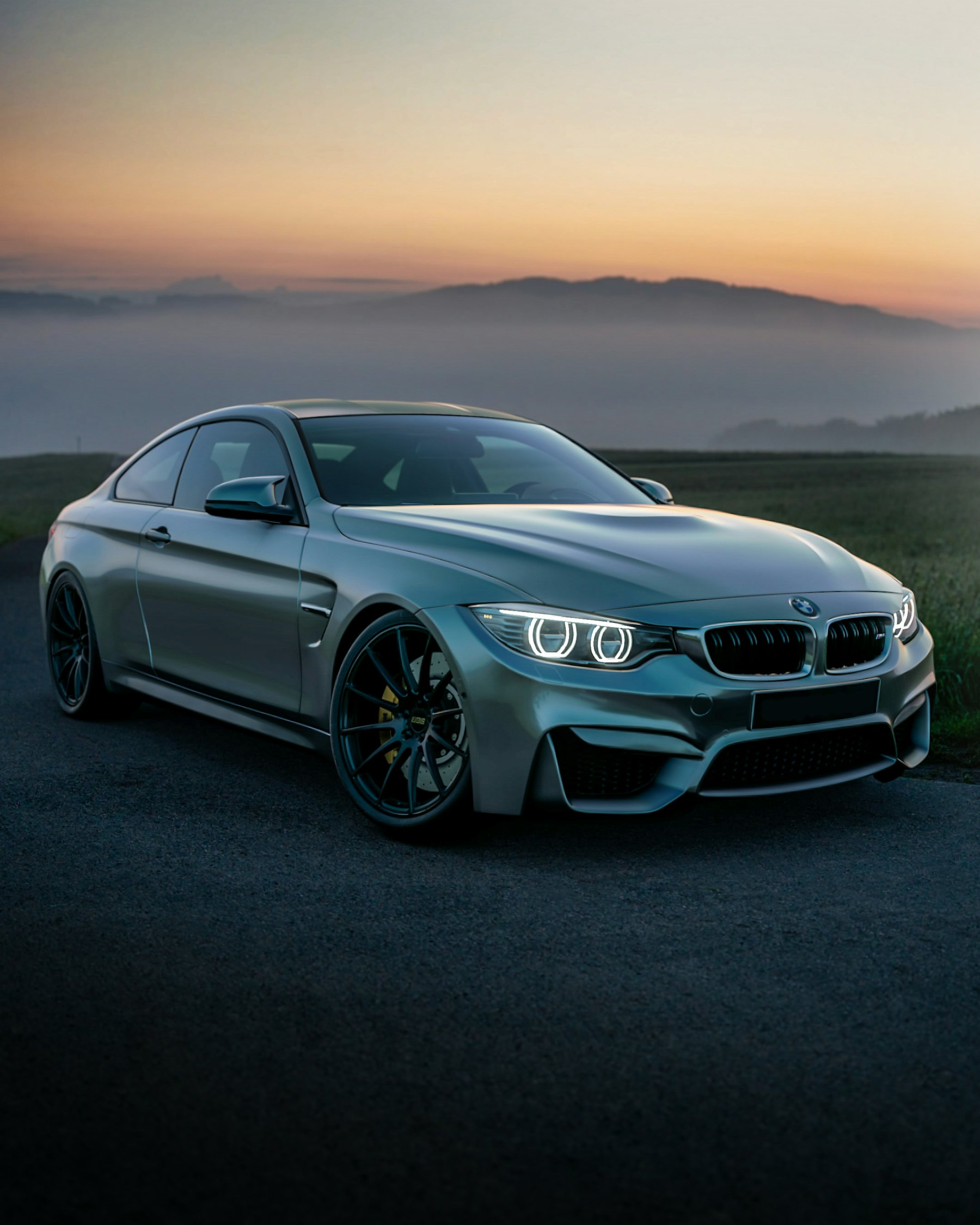 A silver coupé on a country road at dawn, mist in the valley behind