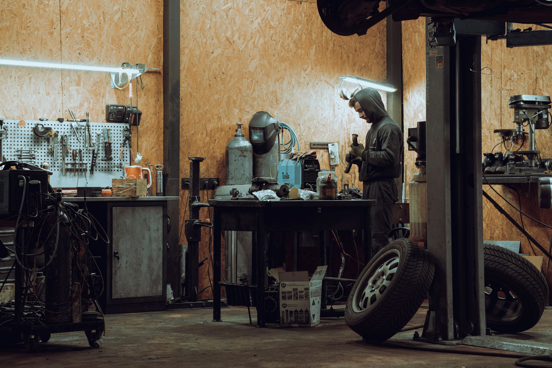 A workshop bench with tools and welding equipment under warm light