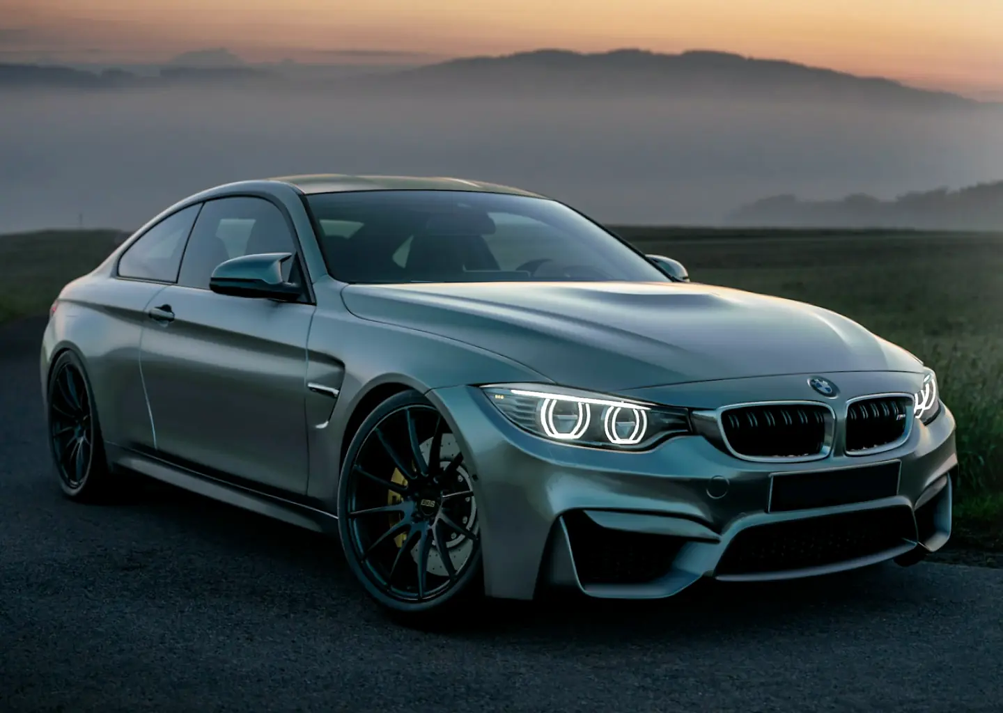 A silver coupé on a country road at dawn, mist in the valley behind