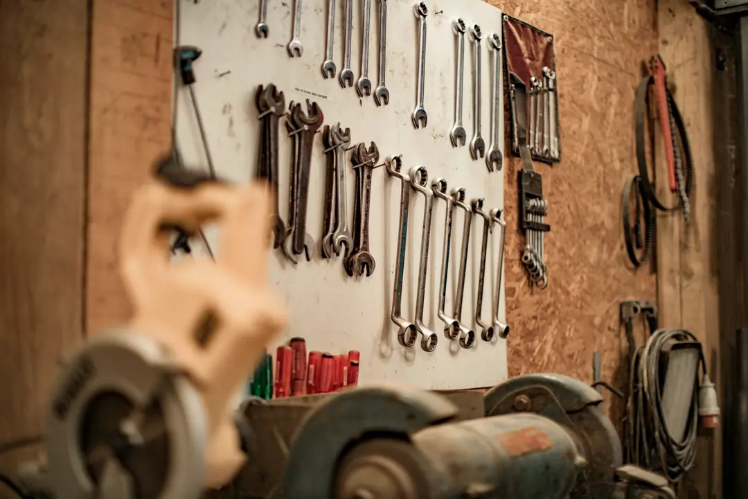 Spanners hung on a pegboard in a workshop, a bench grinder in the foreground